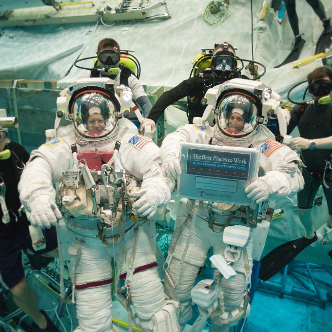 NASA astronauts in action with the agency’s Best Places to Work plaque.