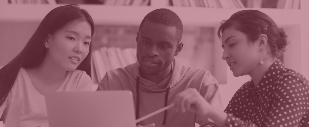 Three young people look and gesture toward a laptop.